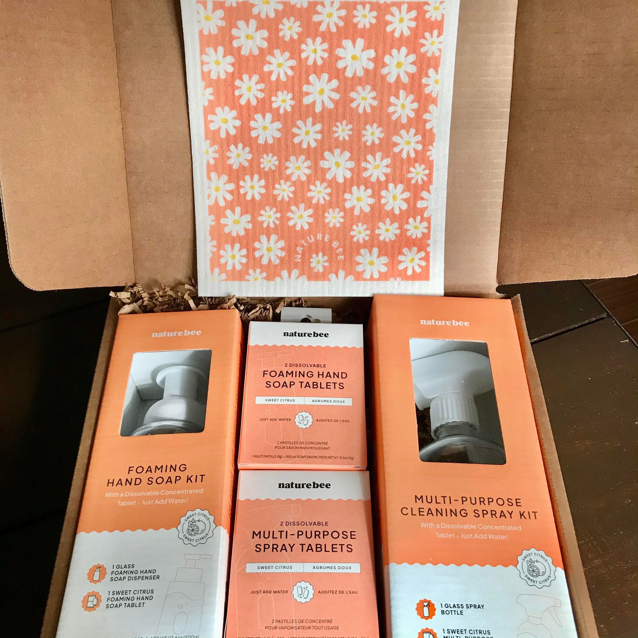 Included in this sweet citrus deluxe giff set is Swedish sponge cloth in a white daisy pattern on an orange background, a foaming hand soap kit,  a multi-purpose cleaning spray kit, a 2 pack of foaming hand soap tablets and a 2 pack of multi-purpose spray cleaning tablets