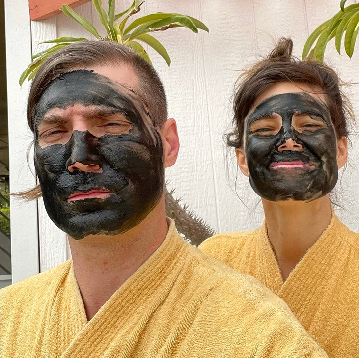 A couple in yellow robes wearing 'Charcoal' Clay Face Mask made in Canada by Birch Babe. It removes toxins, tightens pores, fights breakouts and acne.