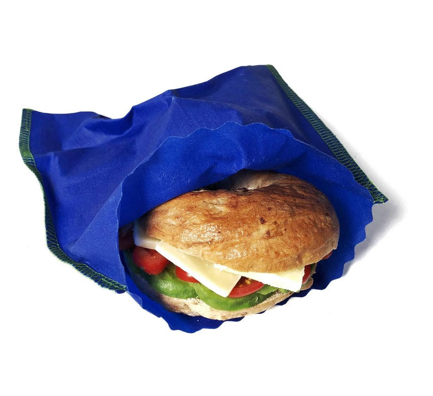 Blue beeswax sandwich bag on a white background shown with a bagel sandwich coming out of it.