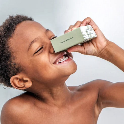 A young boy holds a boxed bar of 100 g blood orange, bergamot and sandalwood hand and body soap.