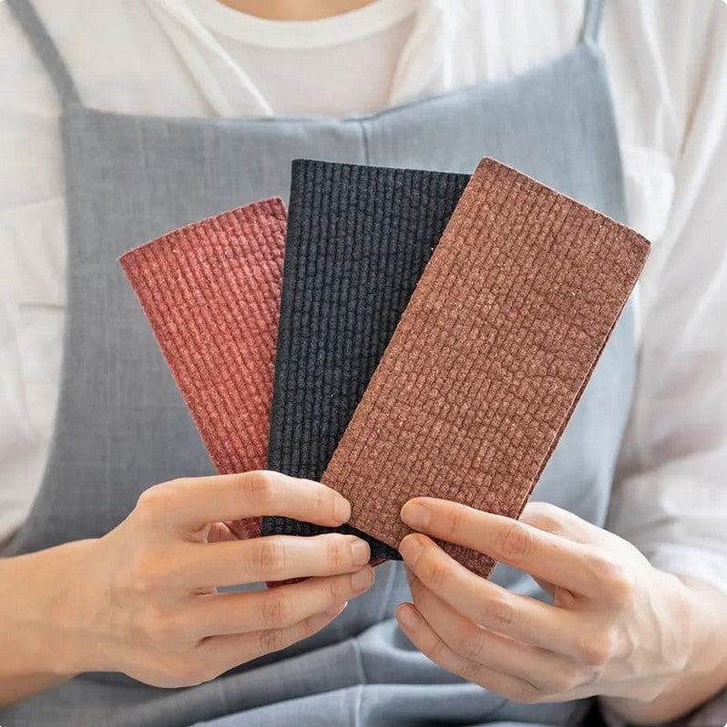 Canadian-made Plantish Wonders of the Earth Swedish dishcloth set of 3 shown in hand – sustainable, absorbent, and compostable kitchen cleaning cloths.