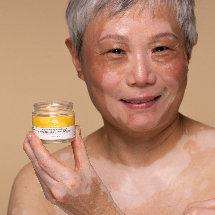 Older woman holding an open jar of Birch Babe face cream which is rich in fatty acids and will help with deep hydration, healing age spots, skins elasticity and fine lines.