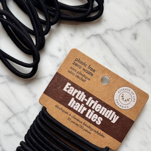 Essence of Life Organics Earth-friendly biodegradable hair ties in plastic-free packaging on marble background