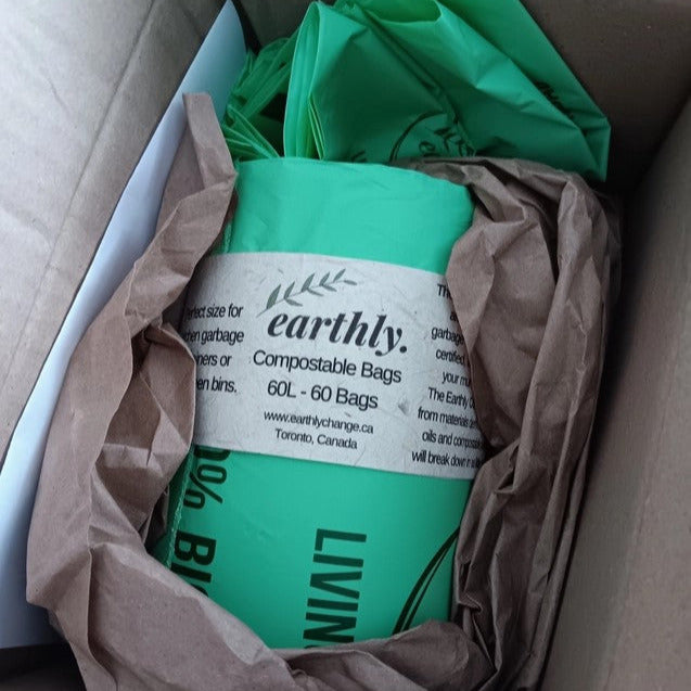 Roll of Earthly 60L compostable garbage bags in cardboard box with recycled paper packaging, labeled 60 bags per roll