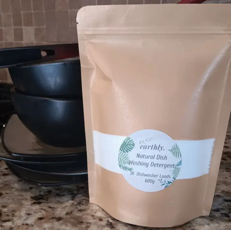 Earthly Natural Dishwasher Detergent in kraft pouch beside clean dishes – 600g, 38 loads, eco-friendly and plastic-free