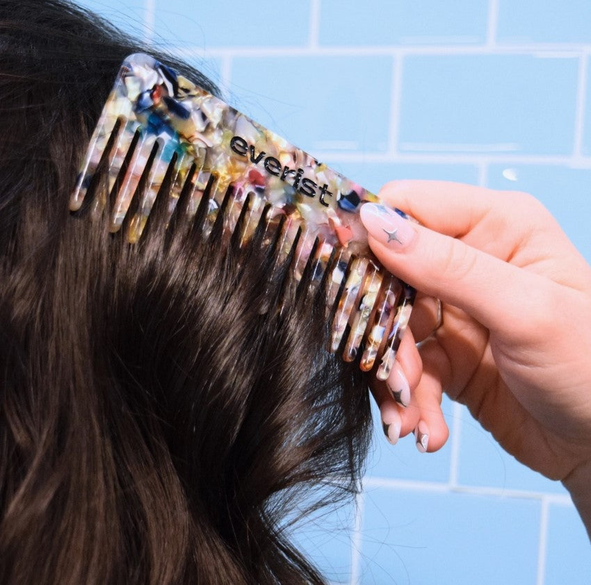 Everist Confetti Comb made from recycled materials gently detangling dark hair in bathroom setting