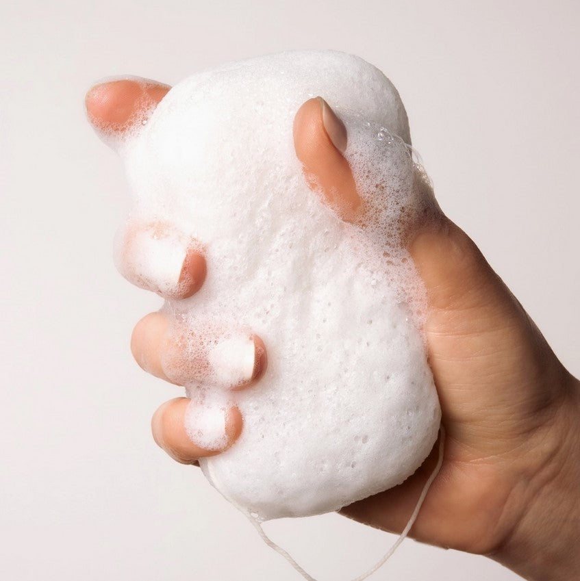 Everist Compostable Konjac Body Sponge in hand creating a rich, foamy lather, highlighting natural exfoliation and zero-waste bath care.