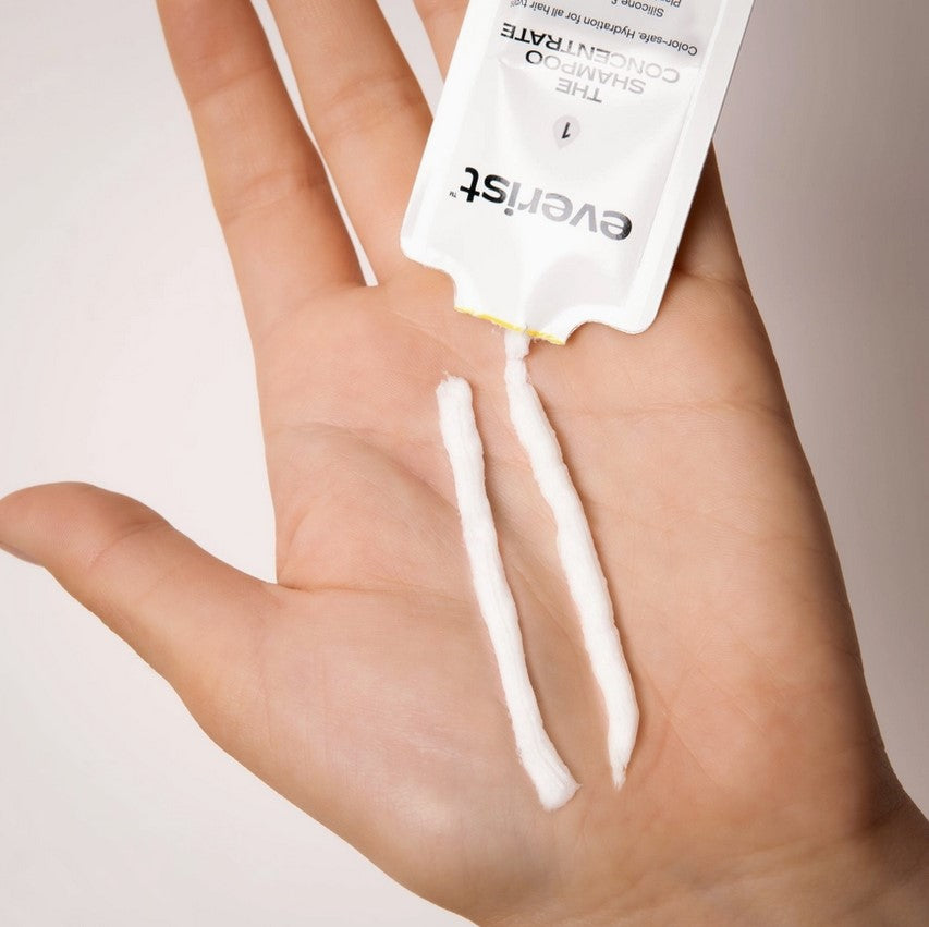 Everist Shampoo Concentrate 10 ml sample being dispensed into hand as creamy strips, demonstrating concentrated waterless formula
