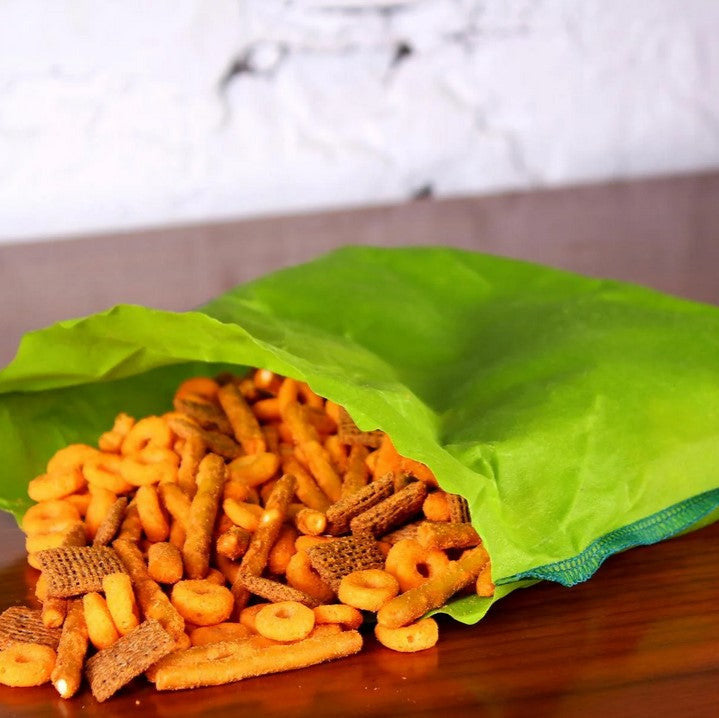 A snack mix is shown coming out of a lime green sandwich bag.
