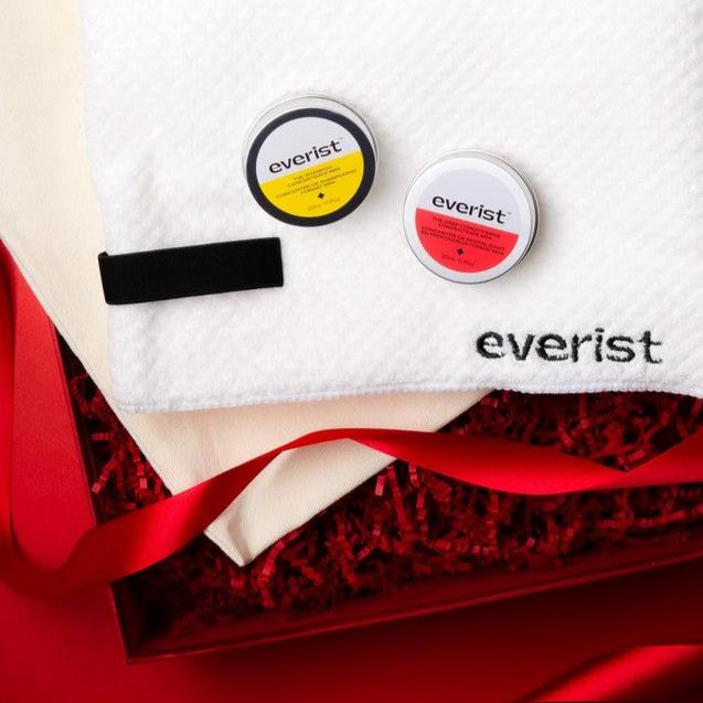 For holiday gift giving purpose this starter set includes the Shampoo Concentrate Travel Mini (20ml / 0.7oz) and the Deep Conditioning Concentrate Travel Mini (20ml / 0.7oz), a Quick-Dry Hair Towel and a  Reusable Canvas Bag is  pictured in a red gift box with red crinkle paper and red ribbon on red background.