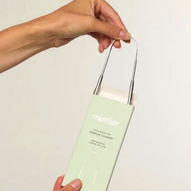 Hand holding Mintier Stainless Steel Tongue Cleaner in eco-friendly mint green box – BPA-free, Canadian oral care tool