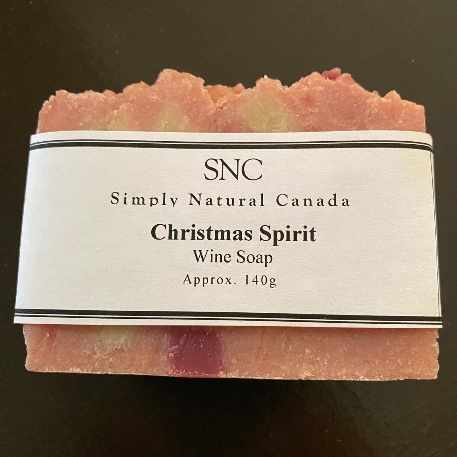 Our Christmas Spirit Wine Soap, a luxurious vegan soap handcrafted in small batches using fruit wine from Kawartha Country Wines in Buckhorn, Ontario is shown on a black walnut table.