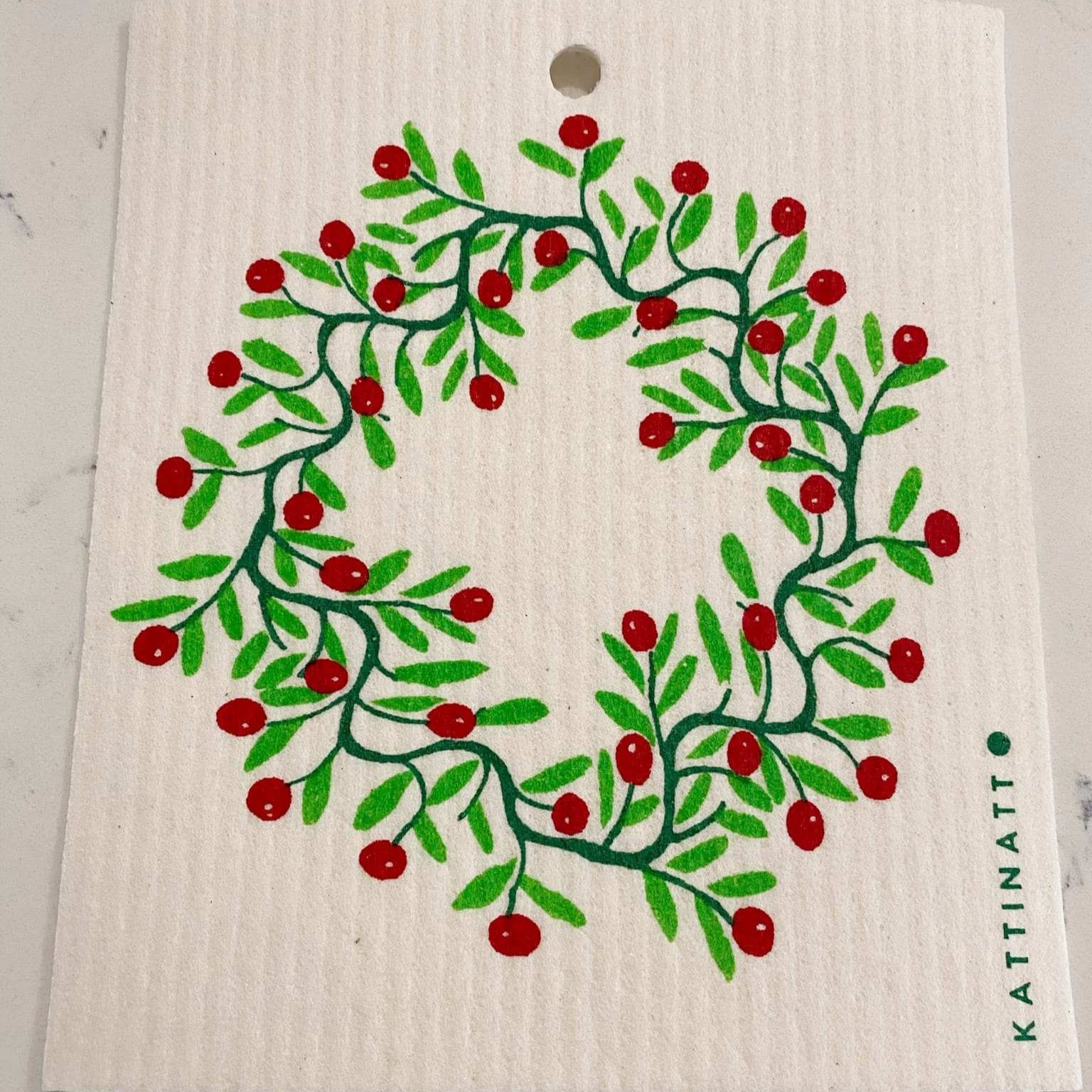 Kattinatt Swedish dishcloth of an artist rendering of a holly wreath with red berries on a white background