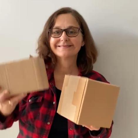 Woman holding two different sizes of Simply Natural Canada mystery boxes packed with personal care and household cleaning eco essentials. Save up to 70 per cent off original prices.