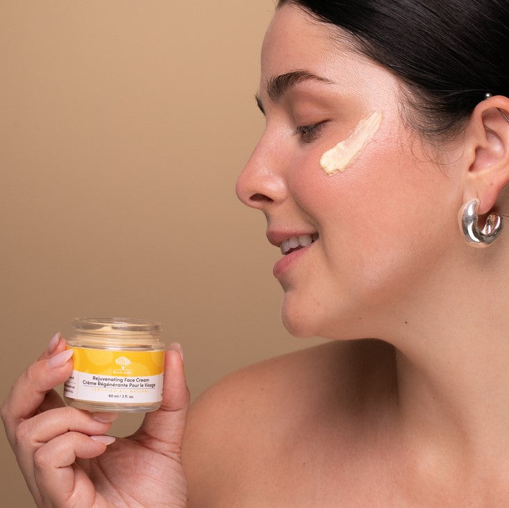 Woman holding an open jar of luxurious Birch Babe face cream which is formulated with many active ingredients like Niacinamide, Panthenol, Peptides and Maple Leaf extract!