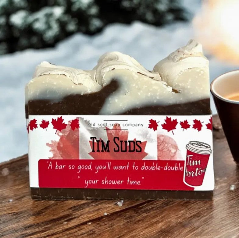 Tim Suds Canadian Bar Soap by Old Soul Soap Company displayed on a wooden surface with snow in the background, featuring a label inspired by Tim Hortons coffee.