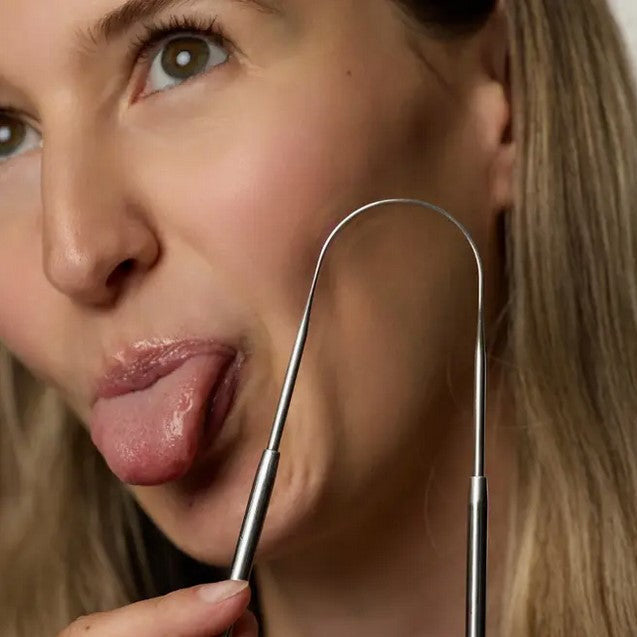 Woman demonstrating Mintier Stainless Steel Tongue Cleaner – natural oral care routine for fresh breath and toxin removal
