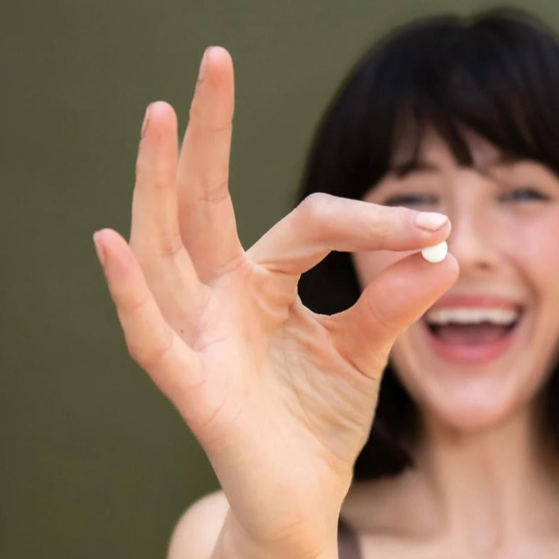 Woman holding a single fresh made toothpaste tablet made in Canada by Tanit