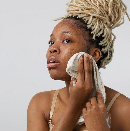 Woman wiping up the lather on her face from a bar of Birch Babe Canadian made facial cleansing soap with activated charcoal