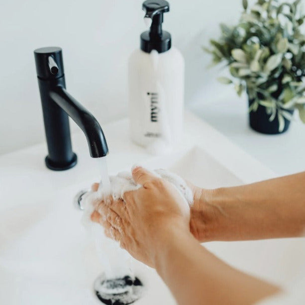 Hands being lathered up in a bathoom sink with Canadian made foaming hand soap from a black and white wheat straw myni foamer pump dispenser