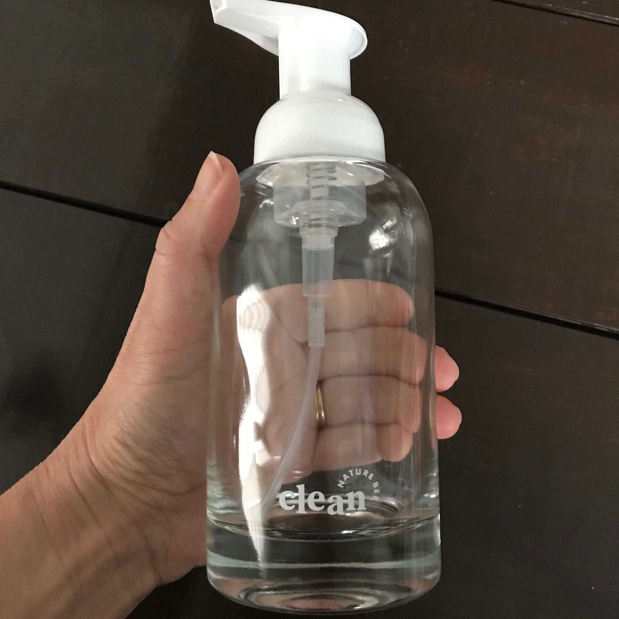 refillable clear glass hand soap foamer bottle with white pump top and white nature bee clean lettering at the bottom front