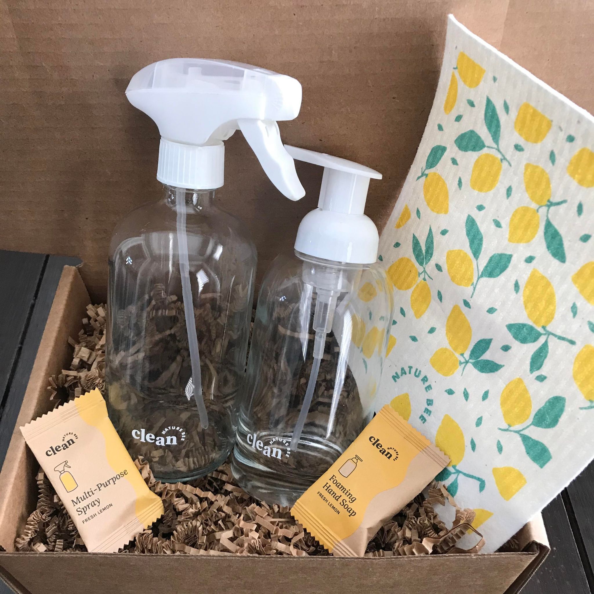 Fresh Lemon refill cleaning starter kit by the Canadian brand Nature Bee Clean comes in a box and includes a Swedish sponge cloth in a lemon pattern, 1 refillable clear glass foamer bottle with white pump top, 1 clear glass spray bottle with white sprayer and 2 tablets - 1 fresh lemon hand soap tablet and 1 fresh lemon multi-purpose spray cleaner tablet
