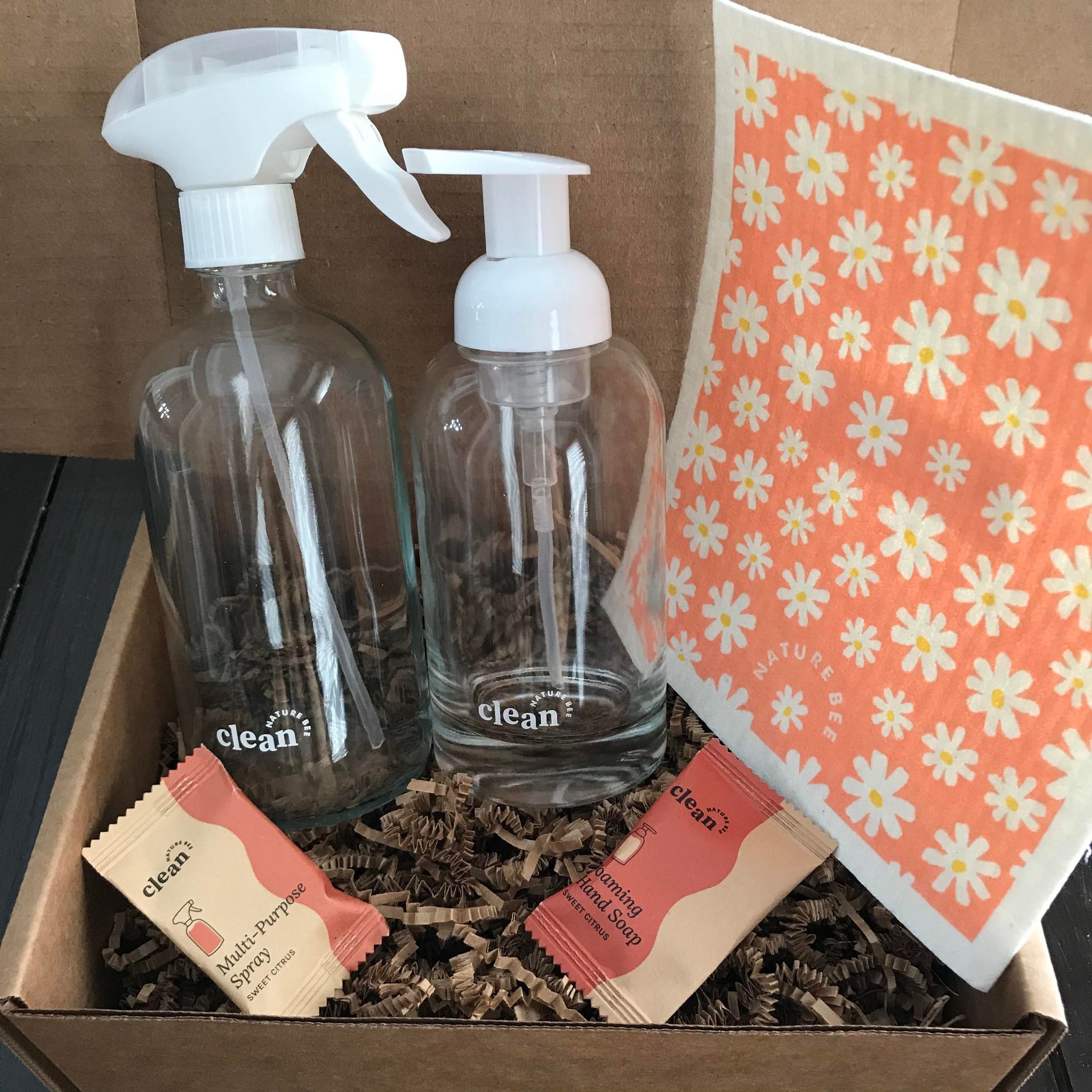 Sweet citrus refill cleaning starter kit by the Canadian brand Nature Bee Clean comes in a box and includes a colourful Swedish sponge cloth in a floral pattern, 1 refillable clear glass foamer bottle with white pump top, 1 clear glass spray bottle with white sprayer and 2 tablets - 1 sweet citrus hand soap tablet and 1 sweet citrus multi-purpose spray cleaner tablet 