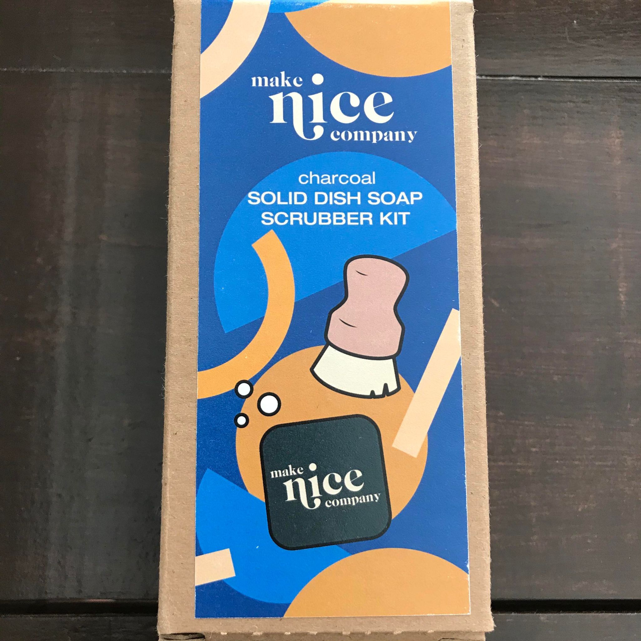 Charcoal solid dish soap block and wood pot scrubber brush set made in Canada by the Make Nice Company and packaged in a brown cardboard box