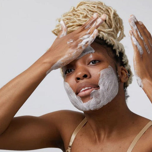 Woman lathering up her face with a bar of Canadian made Birch Babe round facial activated charcoal cleansing soap