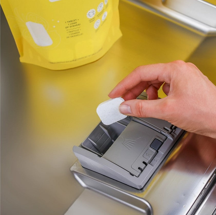 A single Nature Bee Goods dishwasher tablet being put in a dishwasher