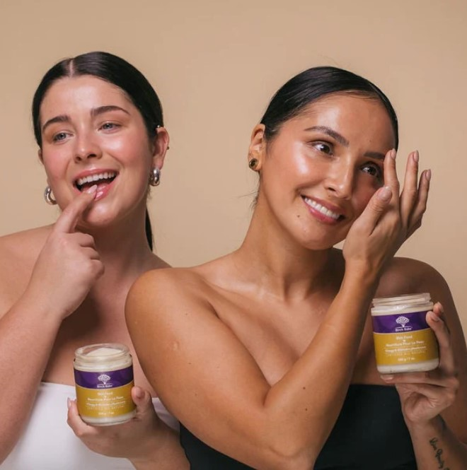 Two women applying skin food on thier bodies one is applying it to her lips while the other is using it to tame her eyebrows