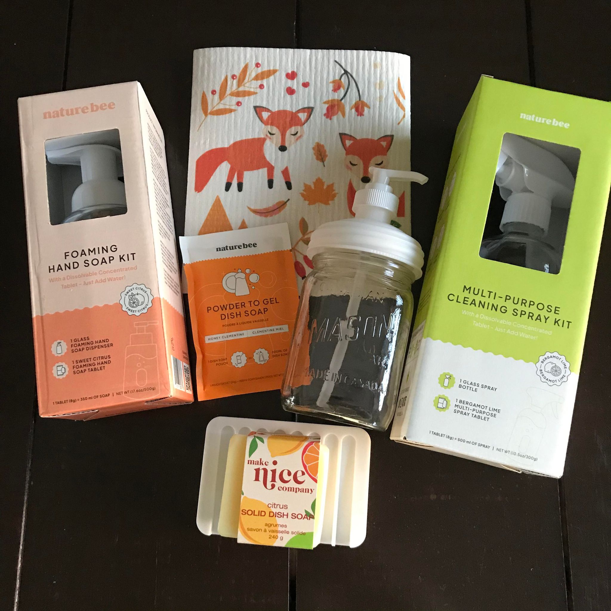 Included in this zero waste kitchen set is a dish soap block (citrus), a white silicone soap dish, foaming hand soap kit (sweet citrus), a powder to gel dish soap (honey clementine),  a vintage Canadian mason with pump top, Swedish sponge cloth (in a festive pattern) and a multi-purpose cleaning spray kit (bergamot lime).