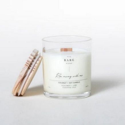 This 'Run away with me' coconut and soy candle scented with bergamot and lime essential oils is made in Canada by The Bare Home and features a wooden wick and a wooden lid. It is pictured on a white background with the lid off.