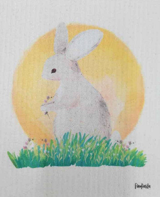 Compostable eco sponge cloth made of cellulose and featuring a rendering of a white bunny reposing on a patch of wild grass cradled by the sun in the background, replaces paper towel by absorbing 20x its weight in liquid. Size 20 x 17 cm