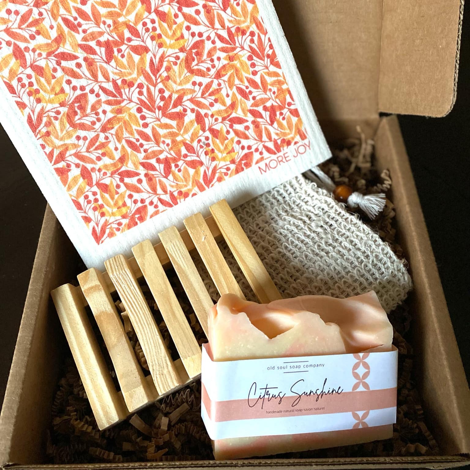 Box containing a soap bar, washcloth, and soap dish with a floral pattern on the soap.