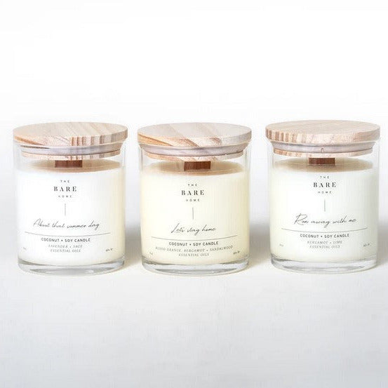 Three candles in clear glass jars with wood tops on a white background. From left to right: About That Summer Day – Lavender + Sage, Let’s Stay Home – Blood Orange, Bergamot + Sandalwood and Run Away With Me – Bergamot + Lime. Candles are all scented with essential oils.
