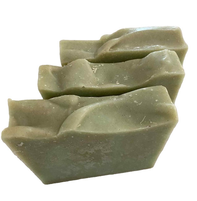 Three green handcrafted essential oil soap bars made in Canada stacked side by side on a white surface