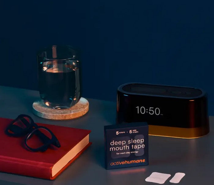 Active Humans Deep Sleep Mouth Tape Starter Pack on nightstand with clock, glass of water, and glasses – bedtime routine