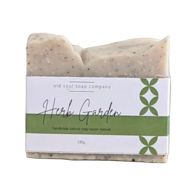 A rosemary, peppermint, and basil essential oil natural soap 180 g on a counter with a Herb Garden wrap around label.