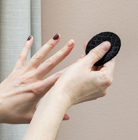 A black sustainable LastRound Pro makeup remover pad being used to remove nail polish