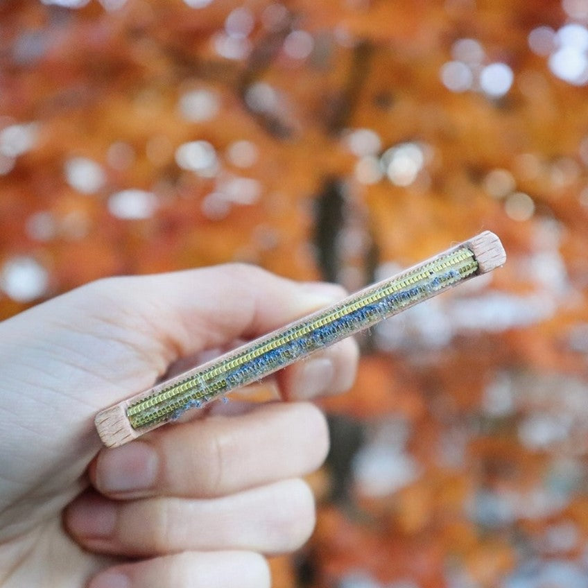 Side view of Plantish Wooden Lint Remover showing slim beechwood handle and brass comb, reusable eco-friendly lint remover