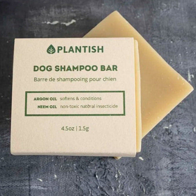 Plantish Dog Shampoo Bar with packaging highlighting argan and neem oil benefits, shown on a dark textured background.