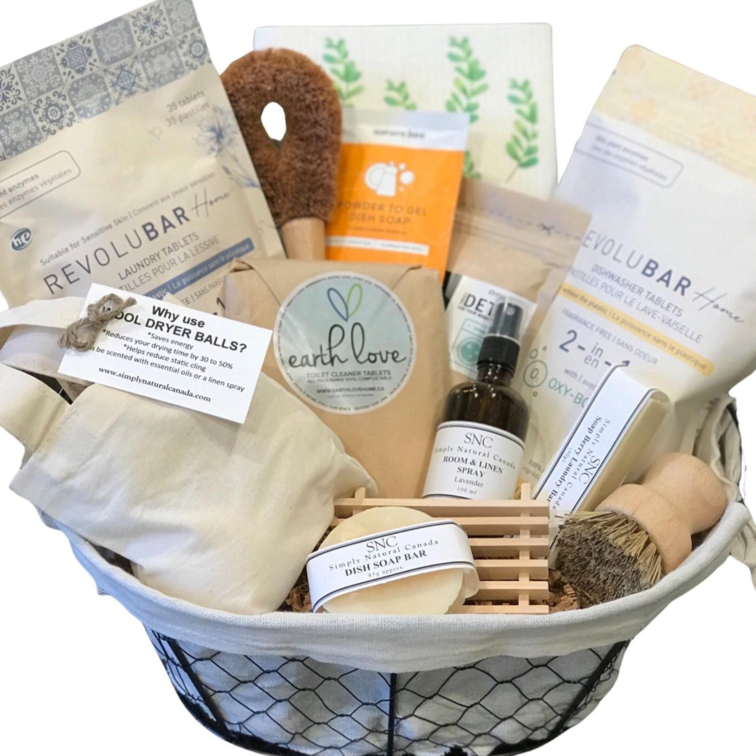This Simply Natural Canada household gift basket full of products from Canadian sustainable brands includes a set of 3 dryer balls, laundry tablets, scouring brush, powder to gel dish soap, a Swedish  dish cloth, washing machine cleaner, dishwasher tablets, toilet cleaner tablets, lavender room and linen spray, laundry stain bar, pot scrubber brush, dish soap bar and wooden soap dish in a fabric lined black wire basket