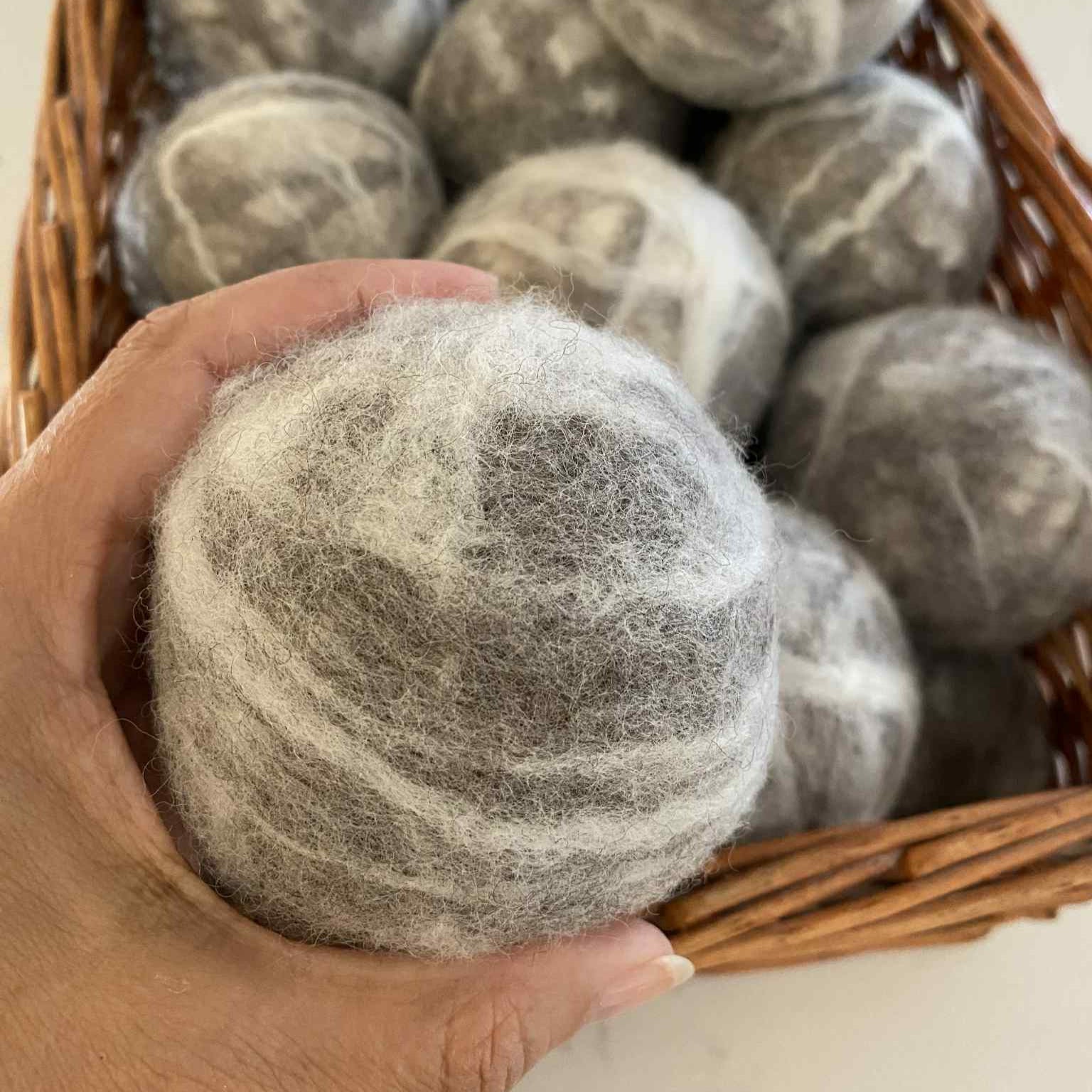 Hand holding extra large SNC wool dryer ball made in Canada – natural reusable dryer ball for faster drying and sustainable laundry.