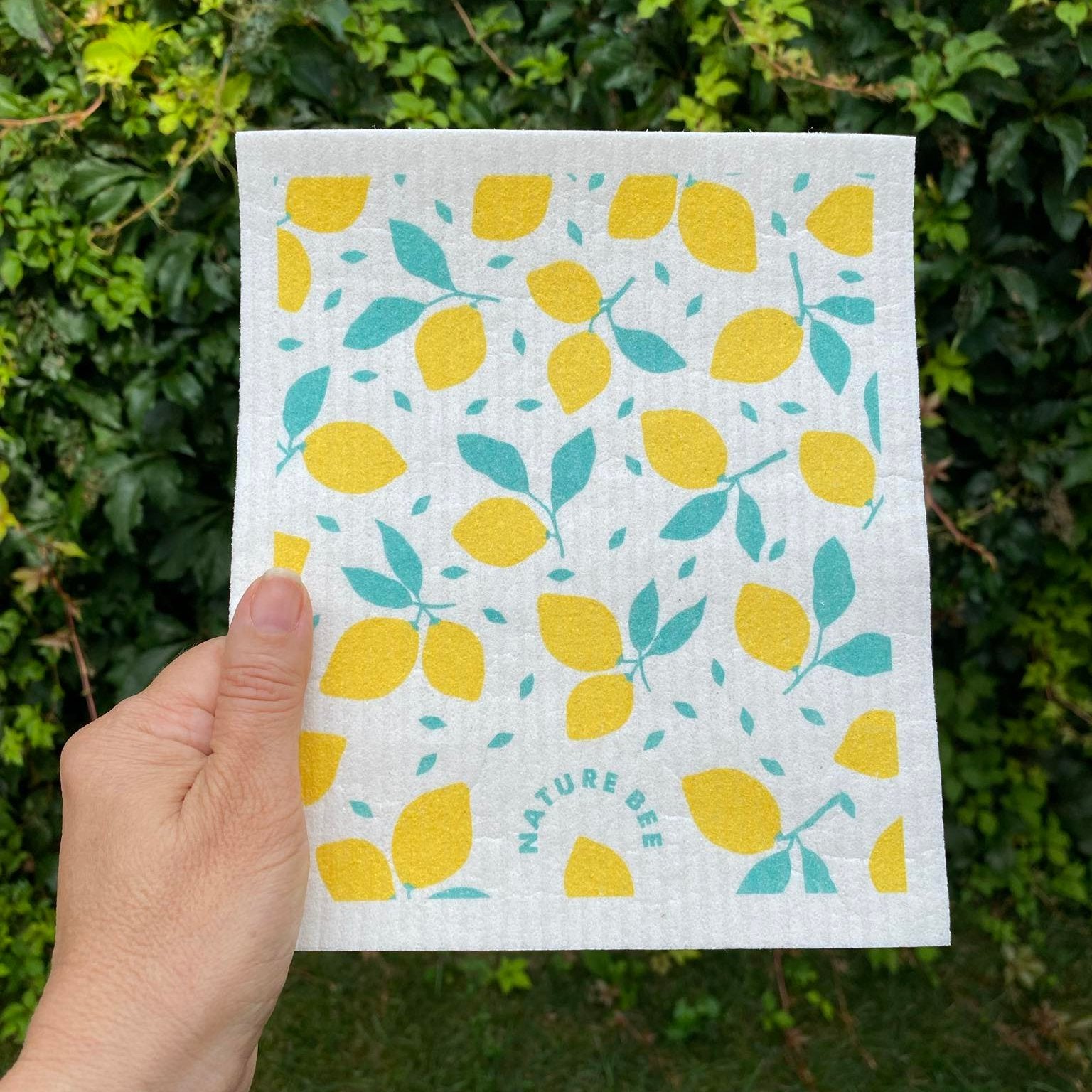 Swedish dishcloth in a pattern of lemons with stems on white background by Nature Bee replaces 17 paper towel rolls and absorbs up to 20x its weight in liquid