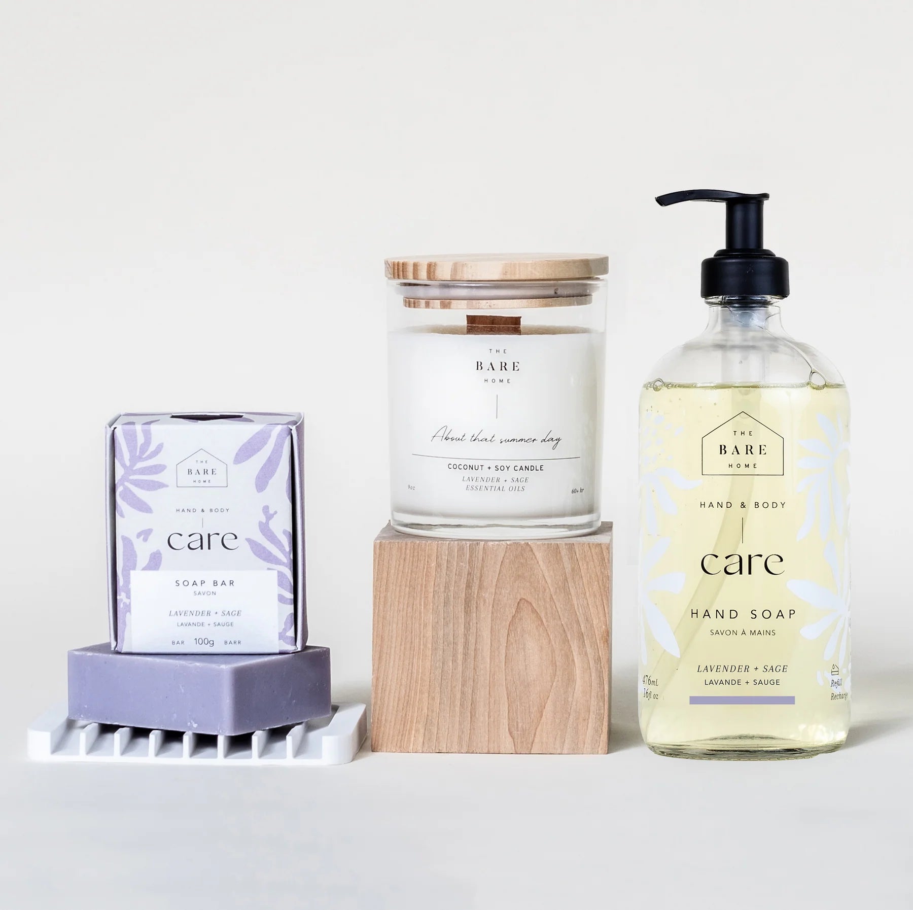 The Bare Home's Care Kit in Lavender Sage is pictured on a white background. It is all natural, eco-friendly and includes a liquid hand soap in a 476ml glass pump bottle, a 100g body bar, candle in a glass jar and white silicone soap dish.