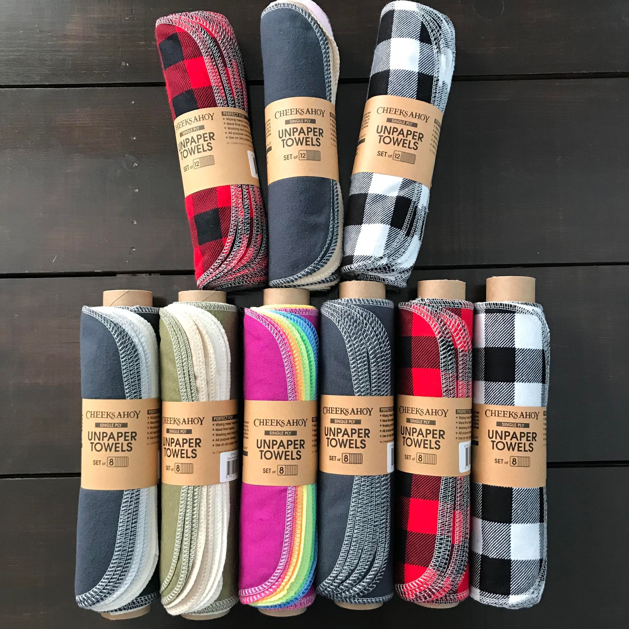 Nine varieties of single ply pre-rolled Unpaper Towels in warm neutral blush, warm neutral charcoal, warm neutral olive, rainbow, red and black plaid, white and black plaid, and charcoal handmade in Canada by Cheeks Ahoy
