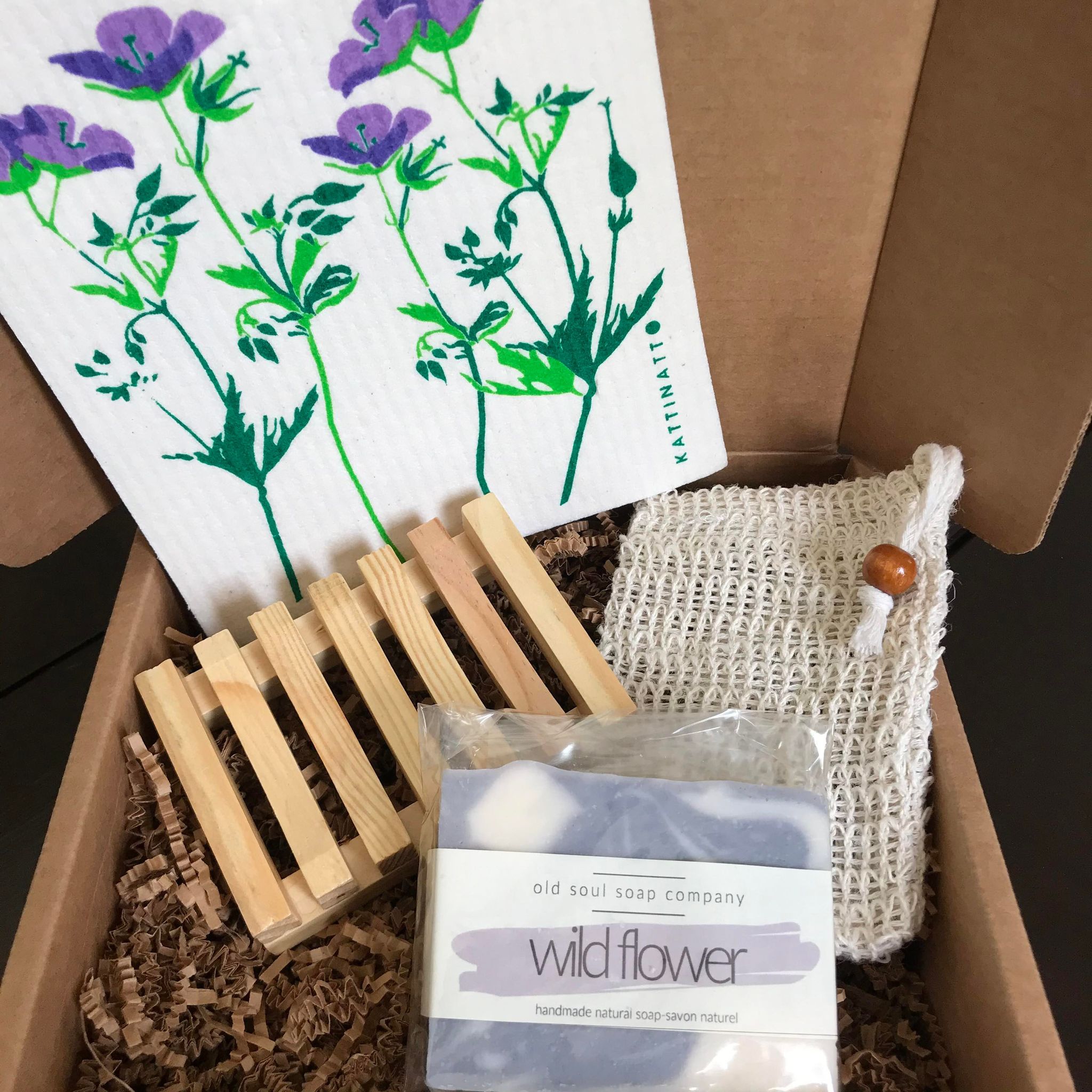 Beautiful handcrafted Canadian made 'wild flower' Old Soul Soap Company vegan soap, wood soap dish, sisal soap pouch body scrubber and Swedish sponge cloth with purple flowers on a white background in a gift box
