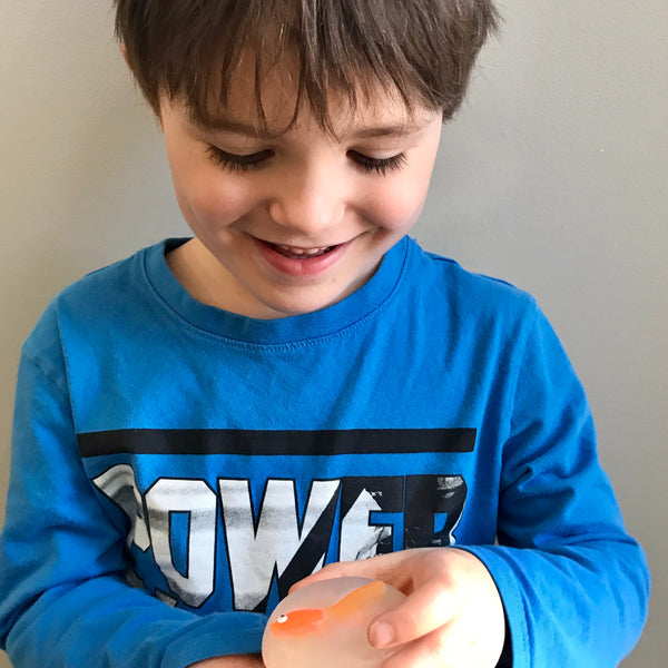 Young boy enjoying a round unscented vegetable glycerin soap with a orange vinyl fish embedded in it