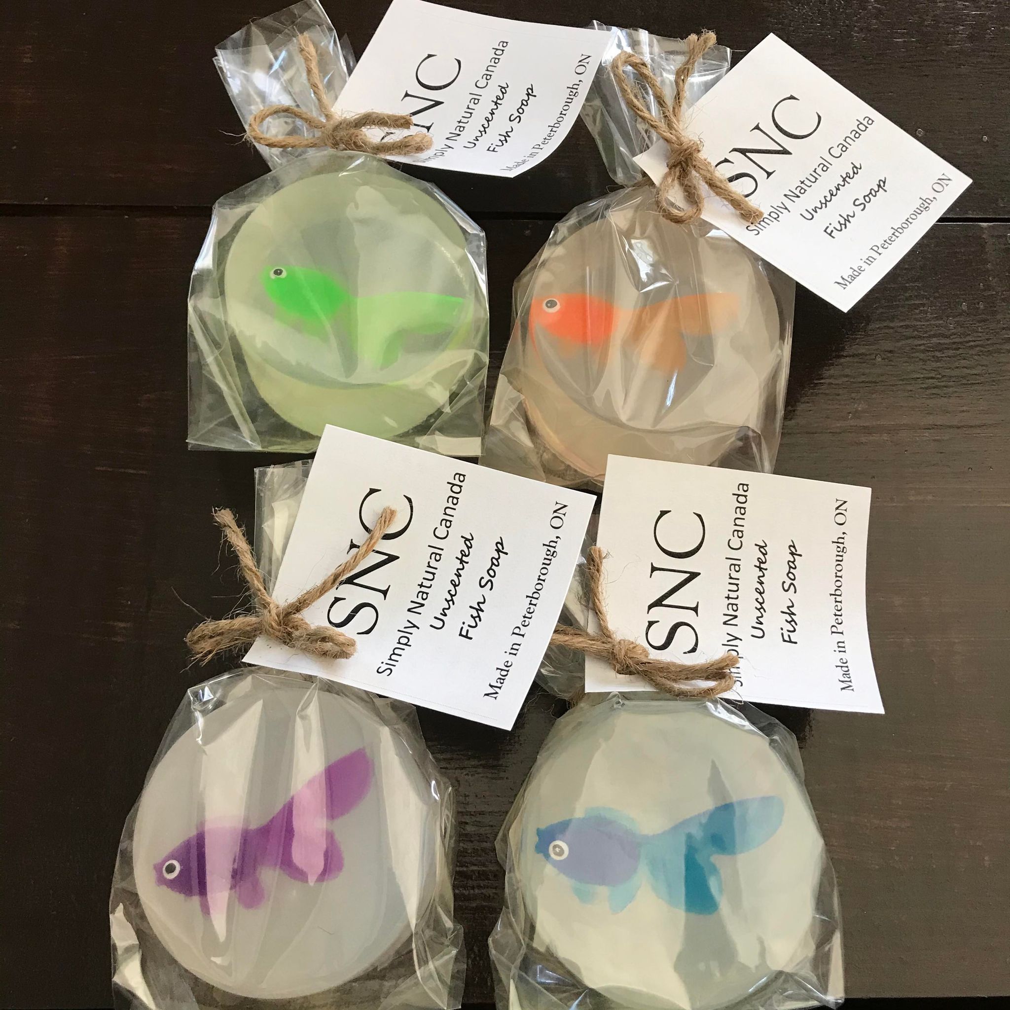 Limited edition simply natural canada round unscented vegetable glycern fish soap with a colorful vinyl fish inside packaged in a compostable bag and sold individually with either a green, orange, purple or blue fish